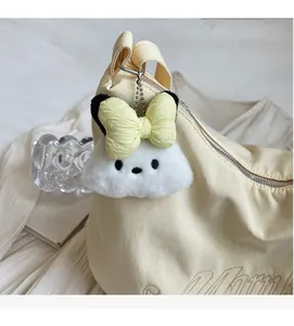 Dettaglio charm orsetto di peluche con fiocco giallo su borsa a mezzaluna beige ricamata