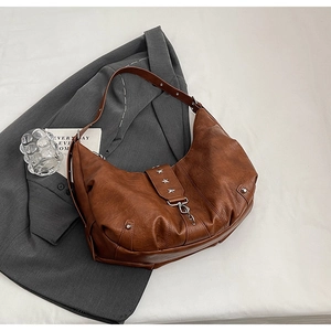 Macro detail of brown leather tote featuring star studs and polished metal hardware buckle