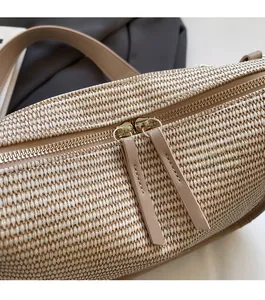 Detail shot of the smooth gold-tone dual zippers and fine beige woven texture of the bag