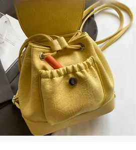 Detail of yellow textured leather mini backpack showing pocket capacity with a lipstick