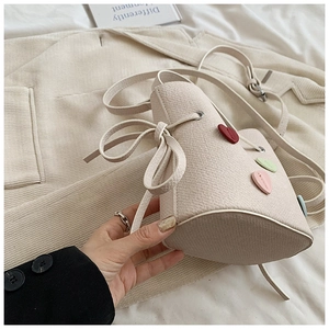 Détail du sac seau crème avec écussons en cuir en forme de cœur et cordon de serrage