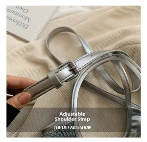 Détail de la bandoulière réglable en argent métallisé avec boucle sur sac en denim