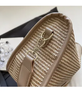Detail of woven straw handbag featuring premium tan leather trim and golden hardware