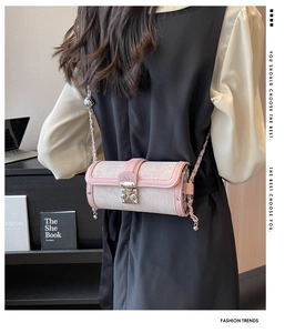 Detail of pink cylindrical chain bag featuring jacquard fabric and silver M-engraved lock