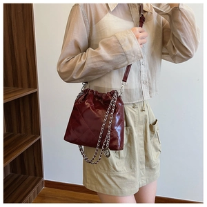 Close-up of quilted burgundy bucket bag with glossy finish and silver chain strap