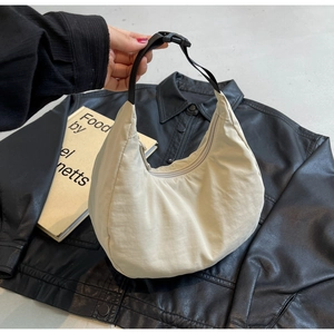 Detail of beige nylon hobo bag showing adjustable strap with plastic buckle and zipper