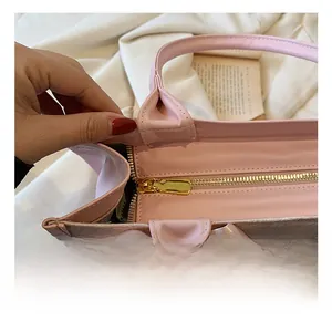 Détail du sac en similicuir rose avec fermeture dorée et nœud décoratif en soie