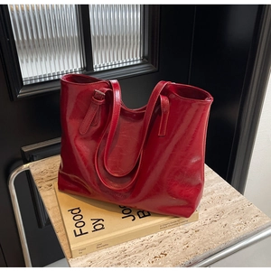 Detail of burgundy glossy leather tote bag showing slim straps and embossed logo