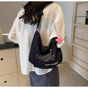 Dettaglio della borsa tote in nylon nero con stampa grafica bianca e ciondolo in peluche