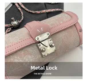 Close-up of pink floral cylinder bag with silver M-letter hardware clasp and chain
