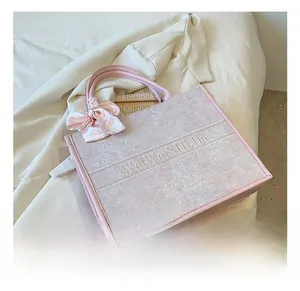 Détail d'un sac cabas en jacquard rose avec broderie et décoration de nœud en soie