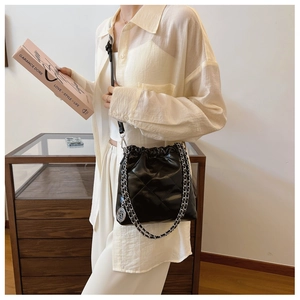 Detail view of black quilted bucket bag with silver chain strap and drawstring closure