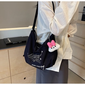 Dettaglio della borsa hobo in tela nera con stampa graffiti e ciondolo in peluche