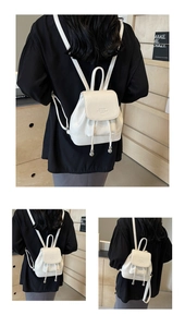 Detailed view of white litchi leather backpack with drawstring closure and metal charm