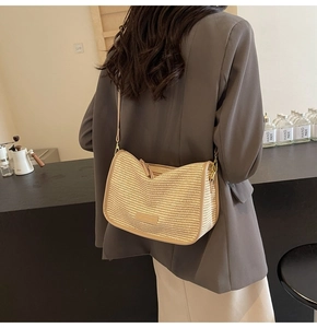 Close-up of woven straw shoulder bag with beige leather trim in a cozy cafe setting