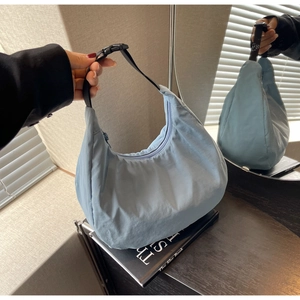Detail view of fog blue nylon dumpling bag with adjustable strap and zip closure