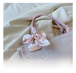 Gros plan sur le tissu jacquard floral rose et le détail du nœud en soie du cabas