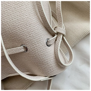 Gros plan sur le cuir grainé et l'oeillet argenté d'un sac seau couleur beige