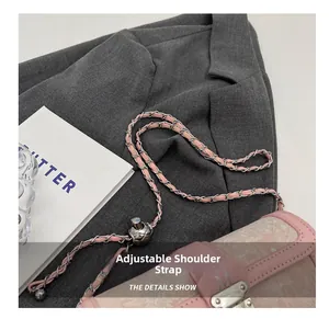 Detailed view of pink chain shoulder bag with adjustable silver ball buckle on grey suit