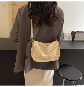 Detail of a beige woven crossbody bag featuring a matching strap and refined metal plaque