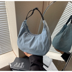 Detailed view of light blue nylon dumpling bag with adjustable black shoulder strap