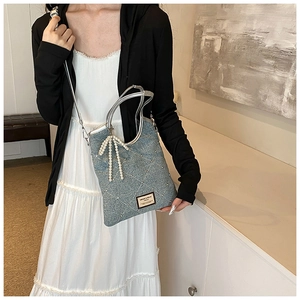 Détail du sac fourre-tout en denim avec motif matelassé et breloque perle nœud