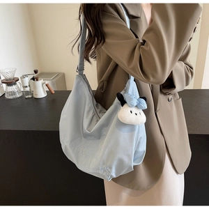 Dettaglio borsa hobo azzurra con ricamo del logo e ciondolo a forma di cagnolino di peluche