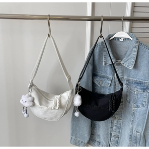 Détail de sacs croissants en nylon noir et blanc avec breloques nuage en peluche