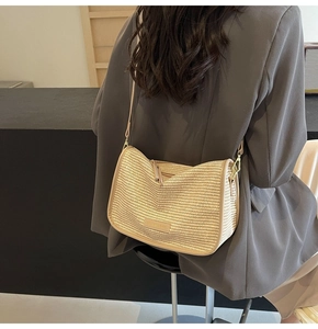 Close-up of a woven crossbody bag with leather trim and fashion label detail