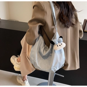 Dettaglio della borsa tote in nylon azzurro con ricamo bianco e ciondolo di peluche