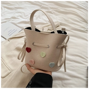 Détail du sac seau crème avec motifs cœurs 3D colorés et texture en cuir grainé