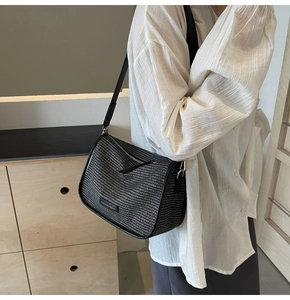 Detail of black woven crossbody bag with leather trim and adjustable shoulder strap