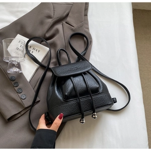 Close-up of black litchi grain leather mini backpack with drawstring and flap closure