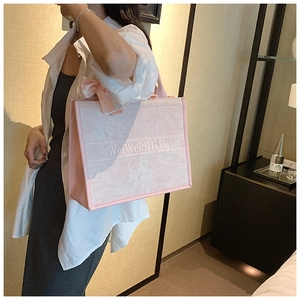 Détail du sac cabas rose avec grand nœud en soie et sangle rayée élégante