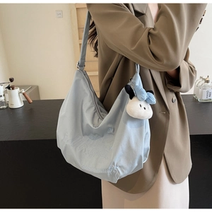 Dettaglio della borsa tote in nylon azzurro con ricamo e ciondolo a forma di gatto