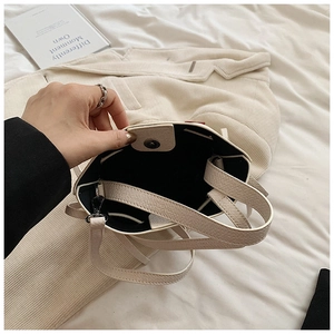 Détail du sac seau crème avec texture litchi et fermeture magnétique métallique