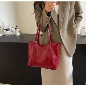 Detail of red oil wax leather tote bag featuring glossy texture and minimalist logo embossing