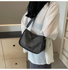 Close-up of woven hobo bag featuring wide black strap and Fashion & Bags decorative tag