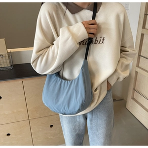 Close-up of light blue nylon crescent bag featuring adjustable black shoulder strap