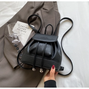 Detail of black pebbled leather mini backpack featuring silver metal beads and drawstring