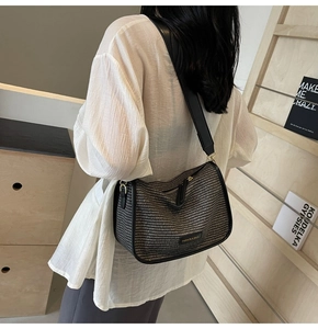 Rear view of woven crossbody bag with brown pattern and black leather trim on model