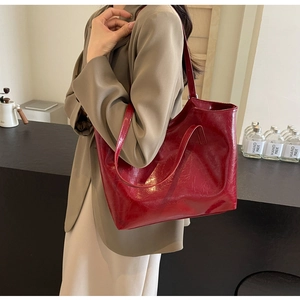 Detail of dark red oil wax leather tote bag with vintage texture and embossed logo