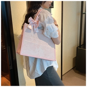 Détail du sac cabas en toile rose brodé avec nœud en soie et poignée en ruban décoratif