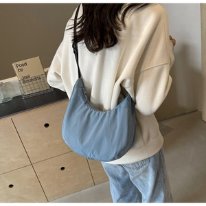 Rear view of a blue nylon hobo bag showing its sleek silhouette and adjustable strap