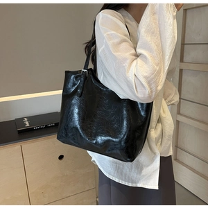 Detail of adjustable silver buckle on black glossy tote bag with crinkled texture