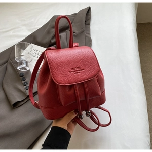 Detail of dark red lychee leather backpack with drawstring closure and flap design