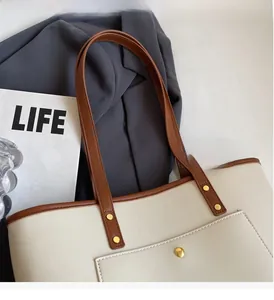 Detail view of cream and brown tote bag with gold rivets and front pocket detail