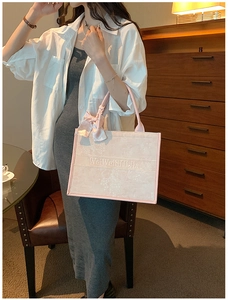 Gros plan du sac cabas fleuri rose avec nœud en soie et broderie de marque