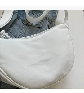 Détail du sac croissant en nylon blanc avec broderie et fermetures éclair métalliques