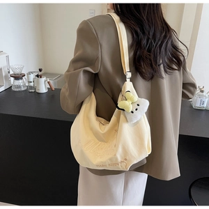 Dettaglio della borsa hobo con ricamo MARN KIEEN e ciondolo in peluche sulla tracolla